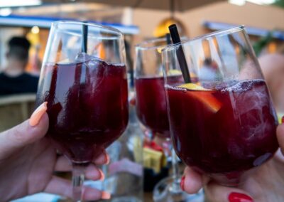 Three full sangria glasses clinking in front of a Spanish building