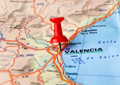 A red pin on a paper map, pointing at the location of Valencia, Spain