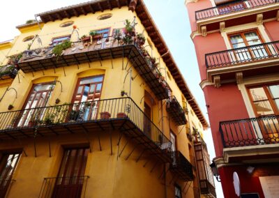 One yellow and one red old town building with balconies and large open windows, Valencia, Spain