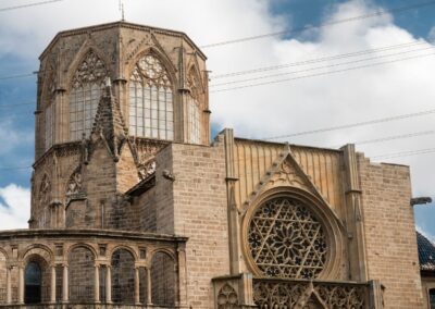 An old cathedral with yellow brick and large windows on a blue cloudy sky. Valencia, Spain