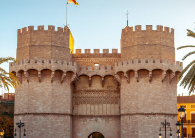 Tourists walking through the gate of Le Torres de Serranos - The Serrans Gate in Valencia on a bright, sunny day.