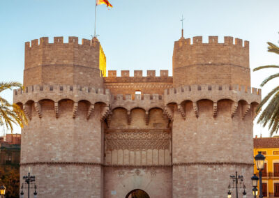 Tourists walking through the gate of Le Torres de Serranos - The Serrans Gate in Valencia on a bright, sunny day.