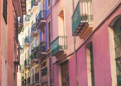 Small alleyway street surrounded by pink old town buildings with balconies looking out