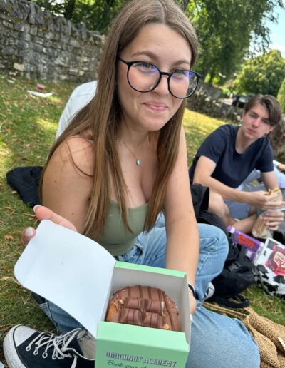 A young girl with glasses holding a box of donuts