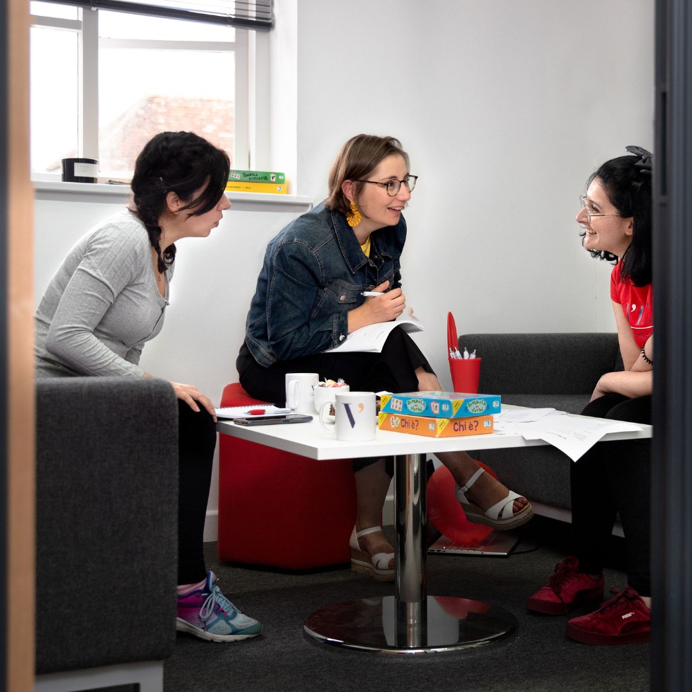 A language teacher giving two people a lesson in a classroom