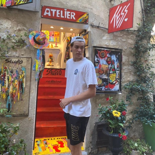 A teenager stood outside a shop called 'Atelier' wearing a cap