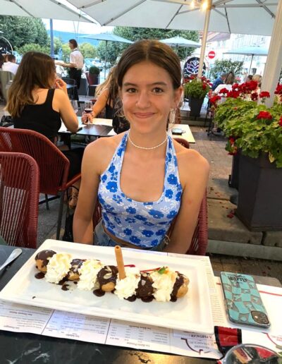 A young girl smilng with a plate of profiteroles