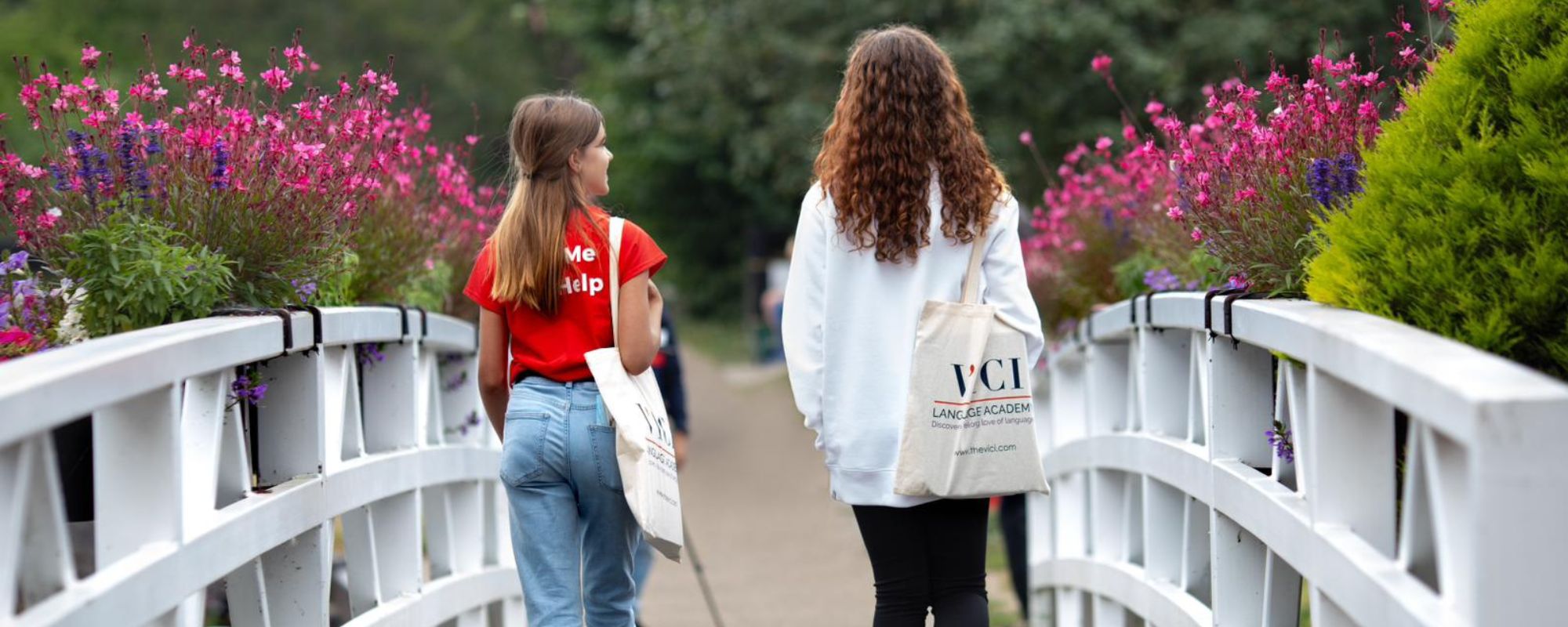 Two young students crossing a bridge with VICI academy tote bags