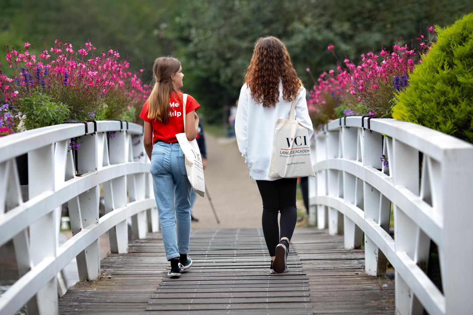 Two young students crossing a bridge with VICI academy tote bags