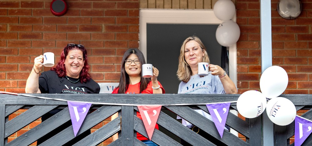 A group of women stood on a balcony with coffee mugs at the VICI Language Academy