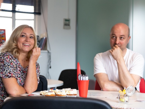 Two smiling adults learning in a bright room