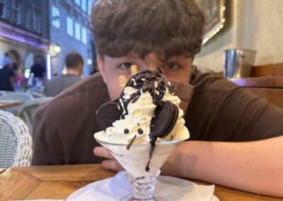 A young boy hiding behind a tall ice cream dessert