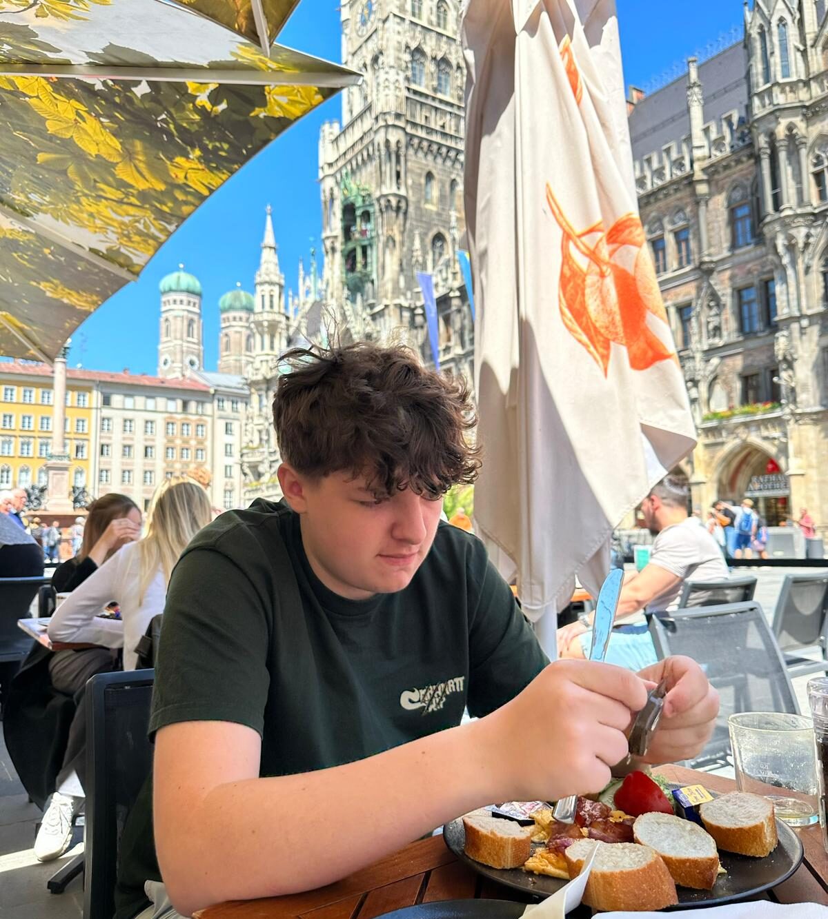 A young teenage boy eating bread and cheese on a sunny square in Europe