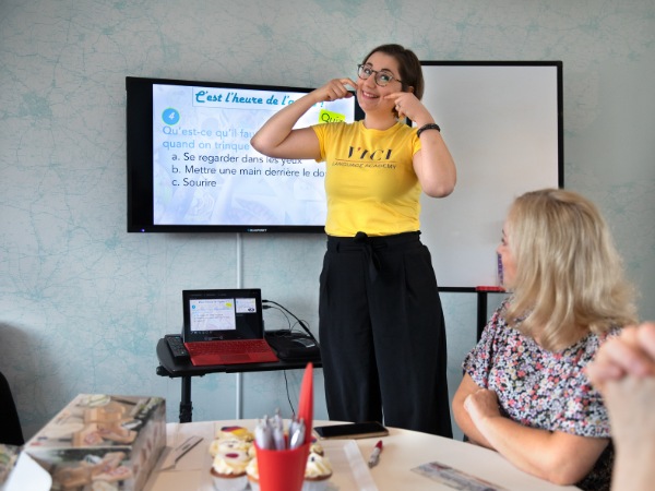 A young teacher in a yellow t-shirt pulling a large smile