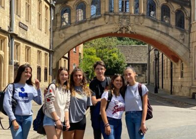 A group of young students smiling in front of the Bridge of Sighs, Oxford on a summers day