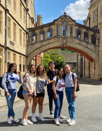 A group of young students smiling in front of the Bridge of Sighs, Oxford on a summers day