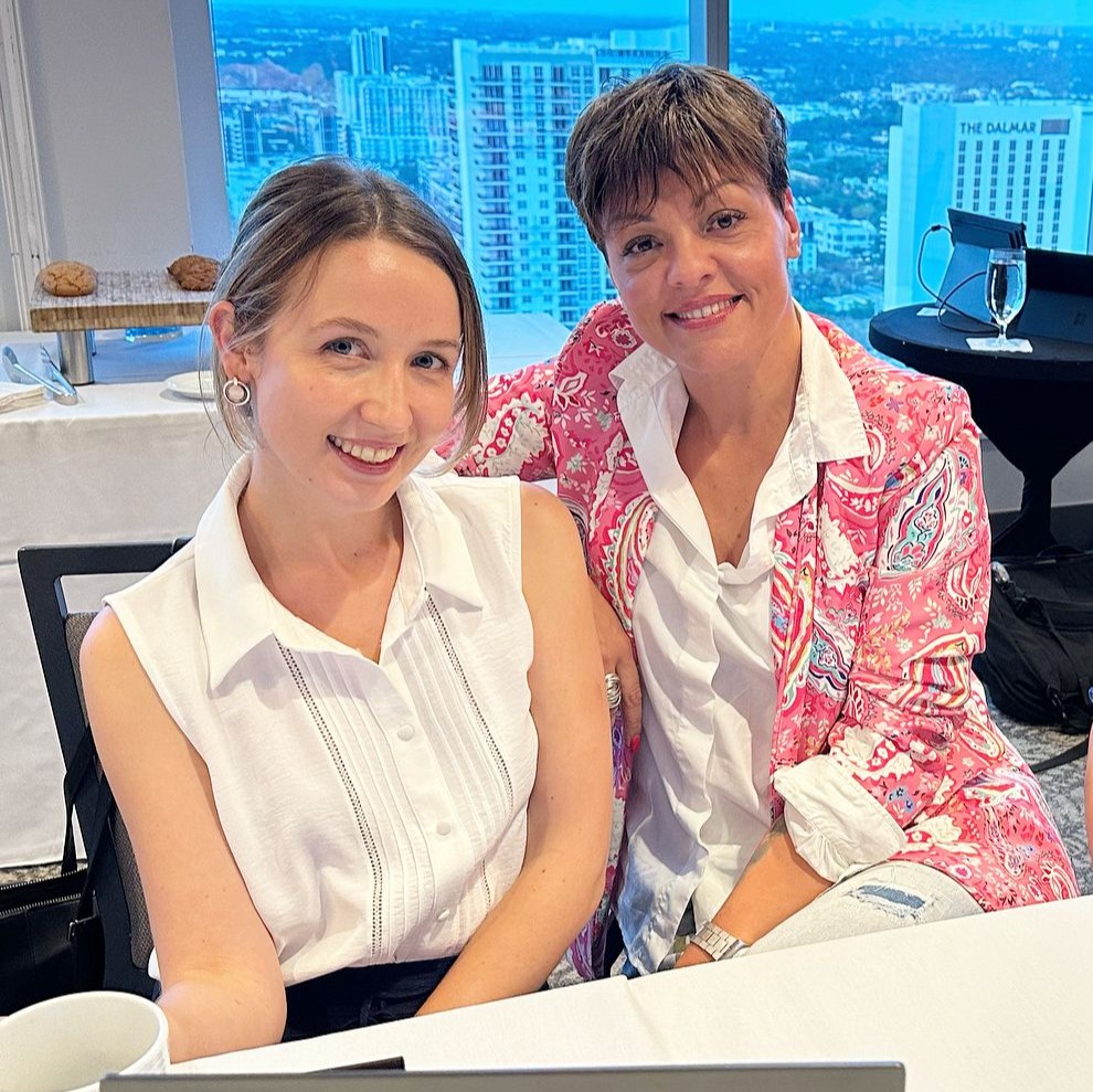Two women sat in an office smiling for a photo