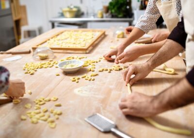 A group of students taking a pasta making class in a bright room