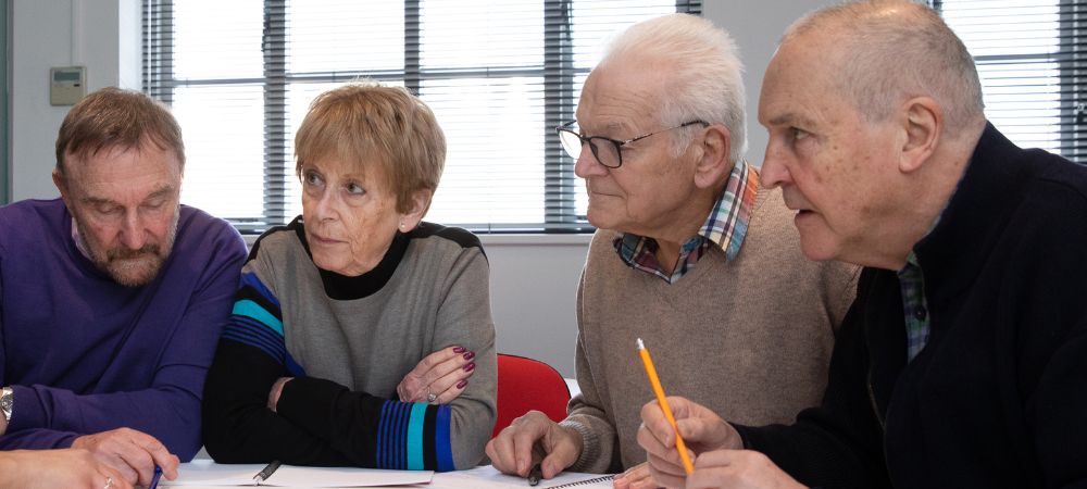 A group of adults gathered around a table having a lesson