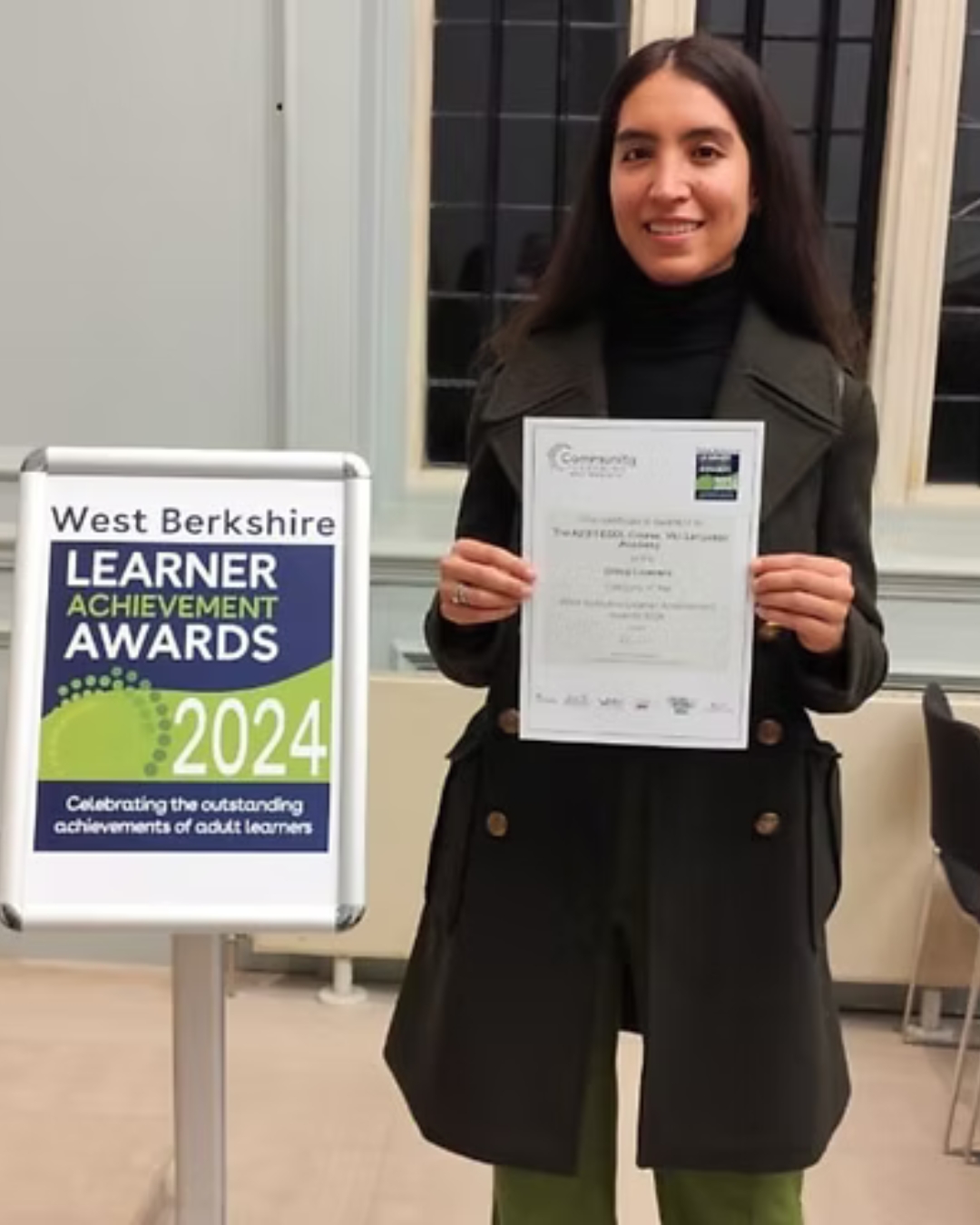 West Berkshire awards A woman holding a certificate next to a green sign