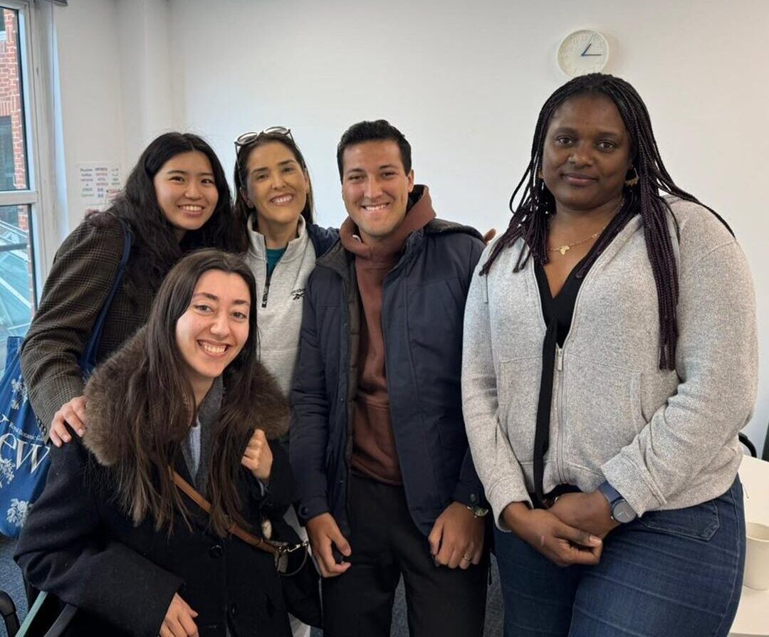 A group of teenage girls stood on a boardwalk in front of a blue ocean on a summers day